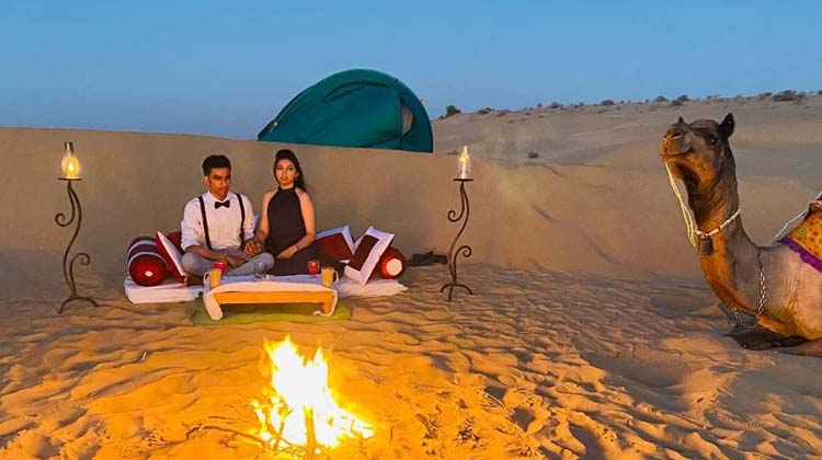 Couple Sitting during Camel Trekking with Overnight Camping in the Arabian Desert